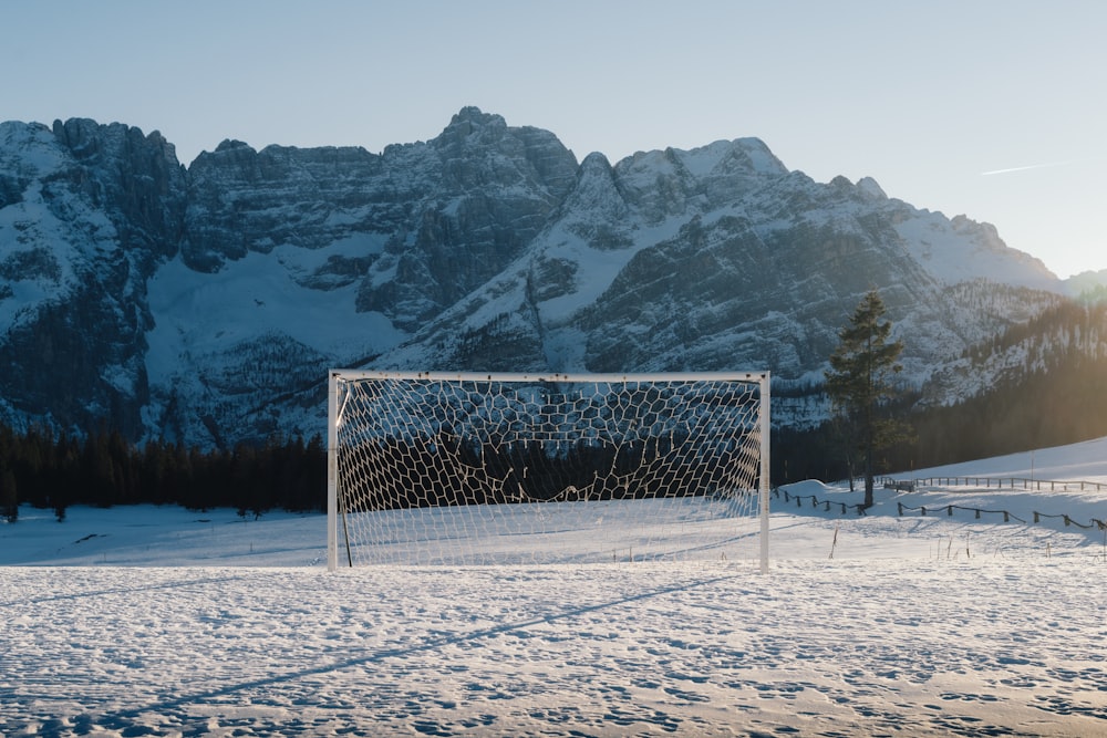 a soccer goal in the snow with mountains in the background