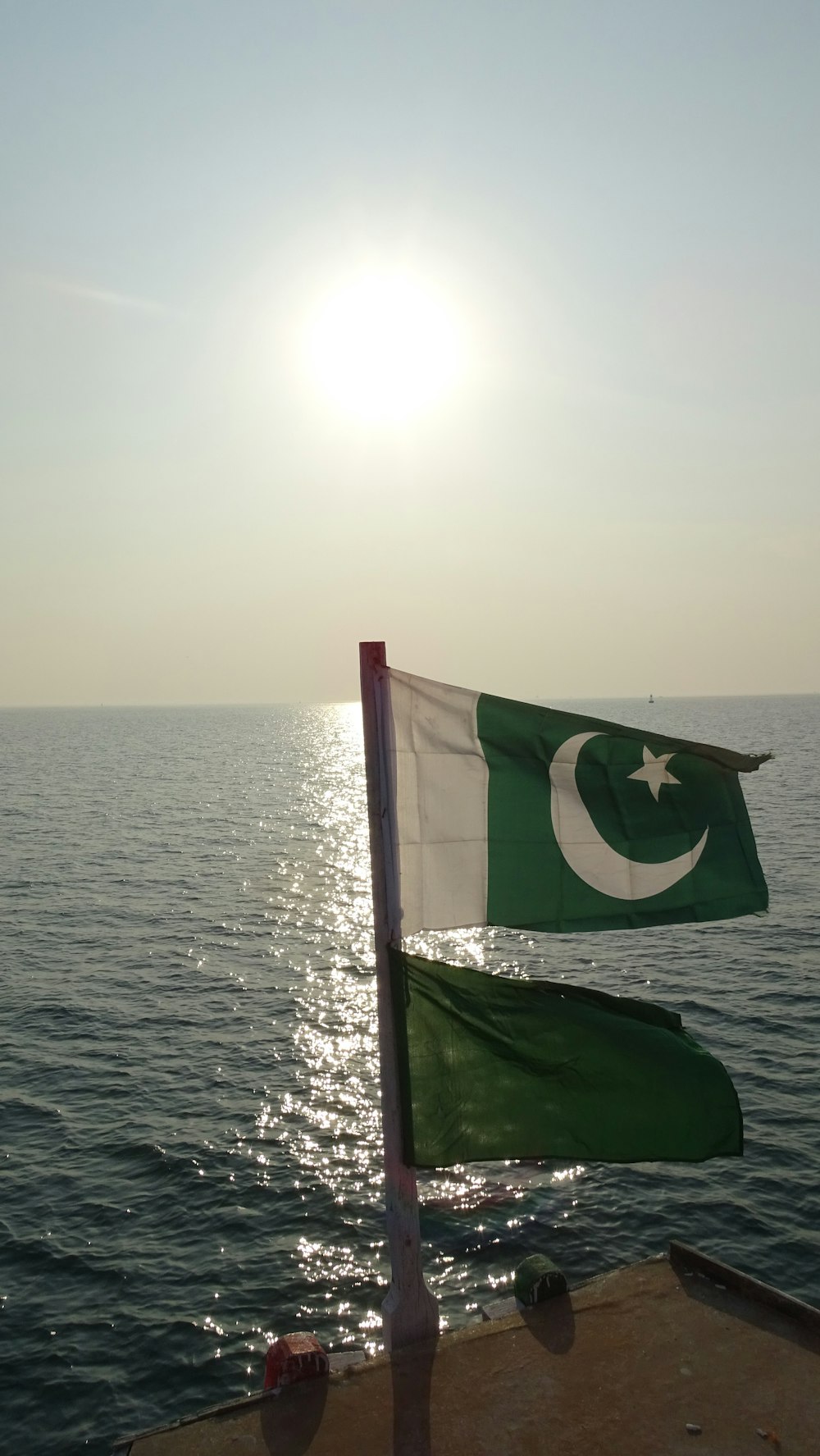 the flag of pakistan and pakistan on a boat in the ocean