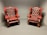 Two vintage, red leather armchairs with tufted backs sit side by side in a minimalist, neutral-colored room. The leather is slightly worn, adding a classic, lived-in feel.