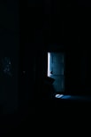 a dark room with a bed and a door