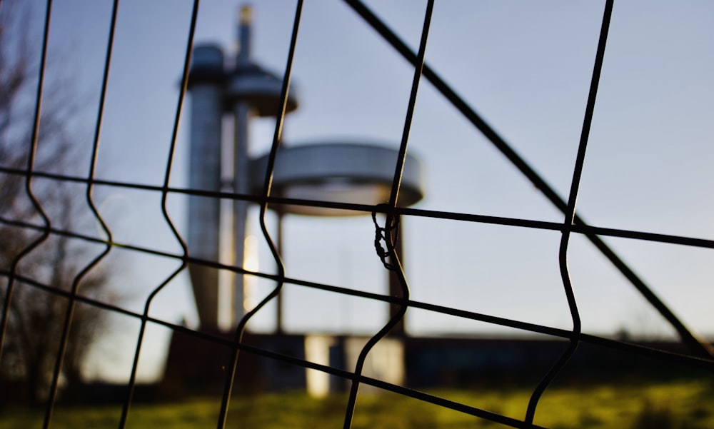 a view of a water tower through a fence
