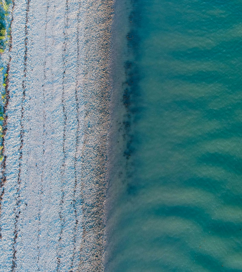 a beach covered in snow next to a body of water