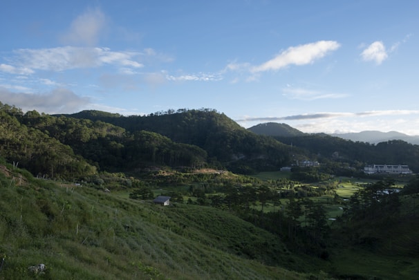A serene hillside view of the eco resort blueprint surrounded by lush greenery under a bright sky.