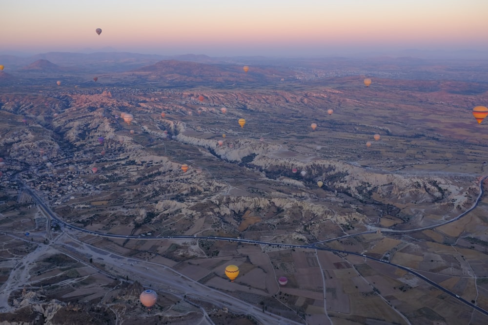 a group of hot air balloons flying over a valley