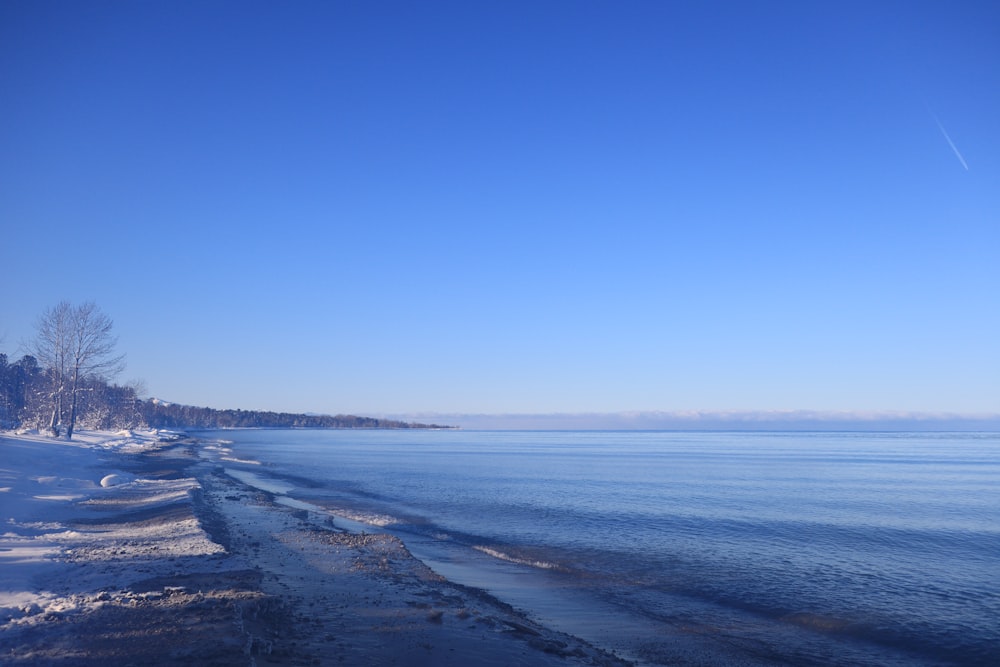 a long stretch of snow covered beach next to a body of water