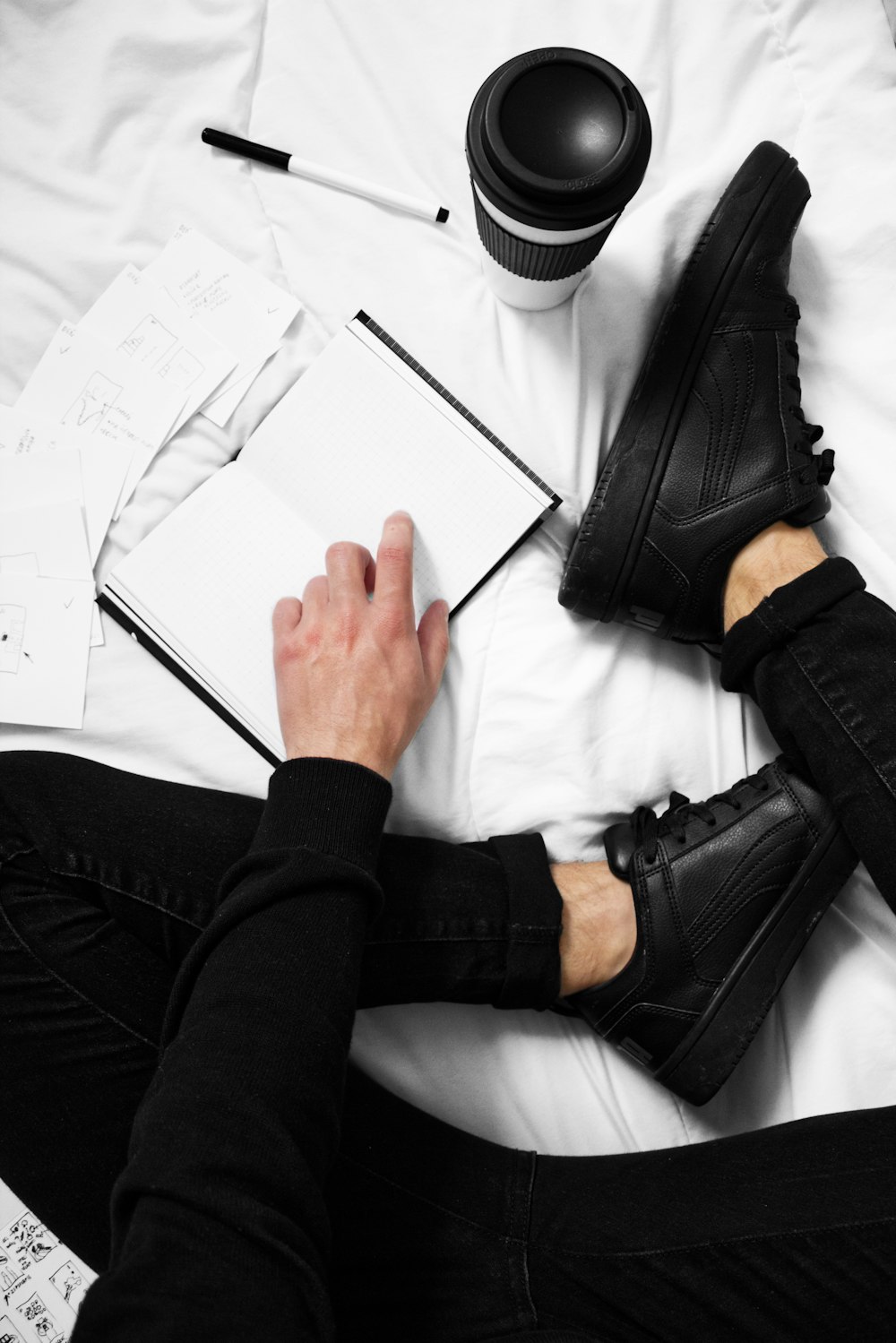 a person sitting on a bed with a book and a cup of coffee