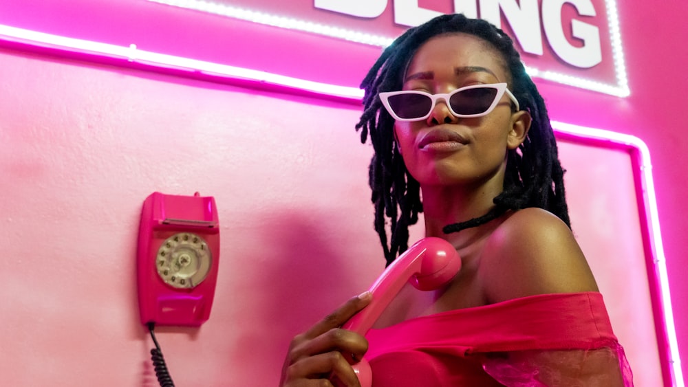 a woman in a pink dress holding a pink phone