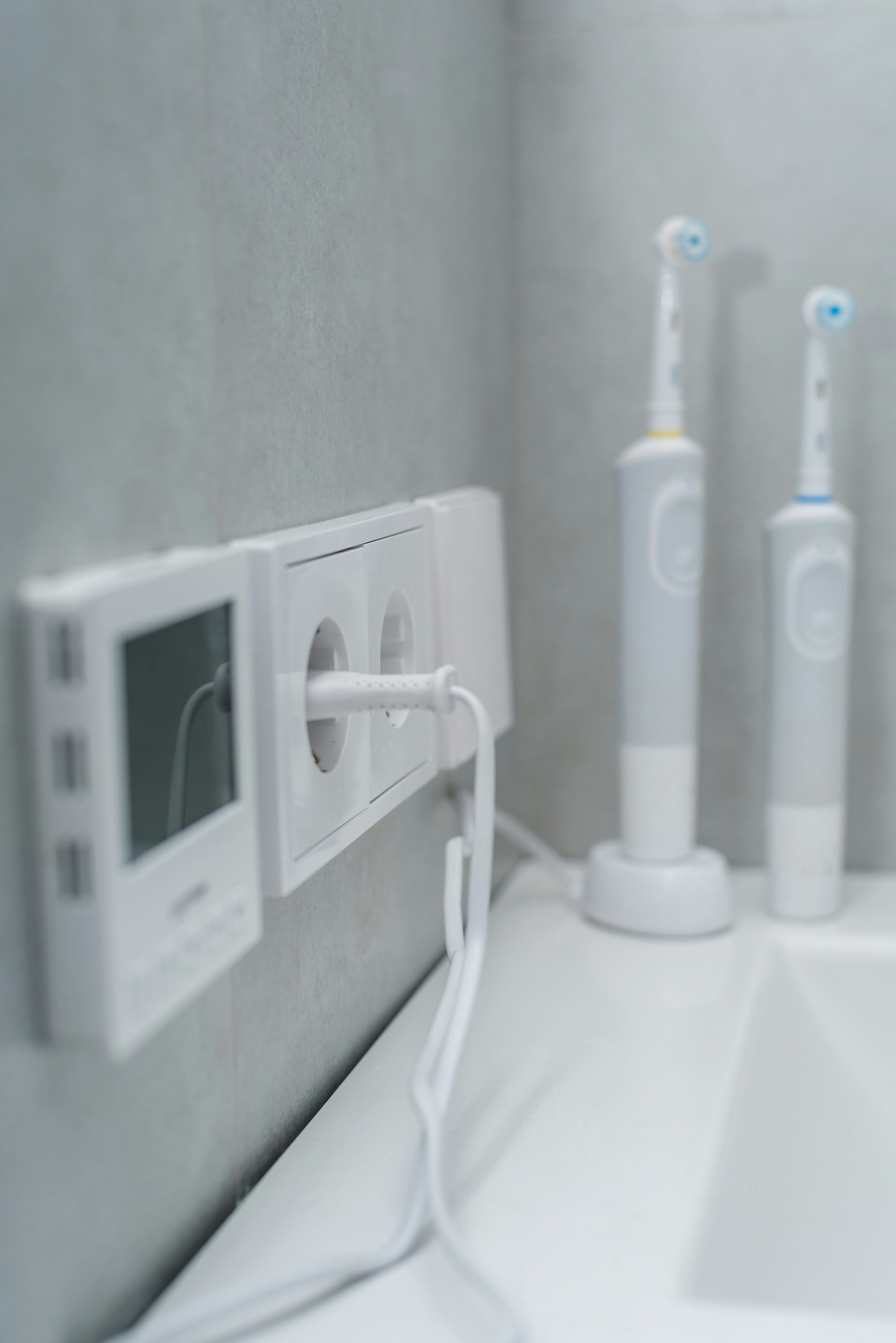 a bathroom with three electric toothbrushes on the wall