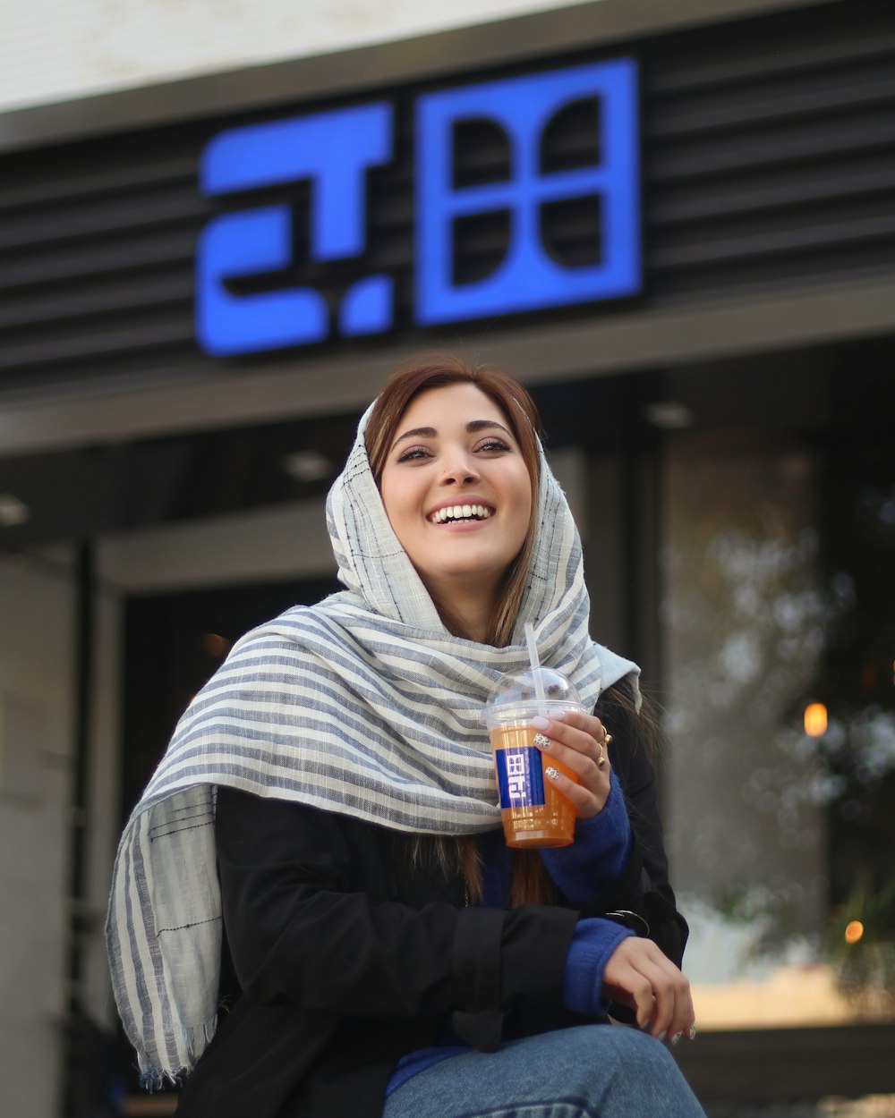 a woman sitting outside of a store holding a drink