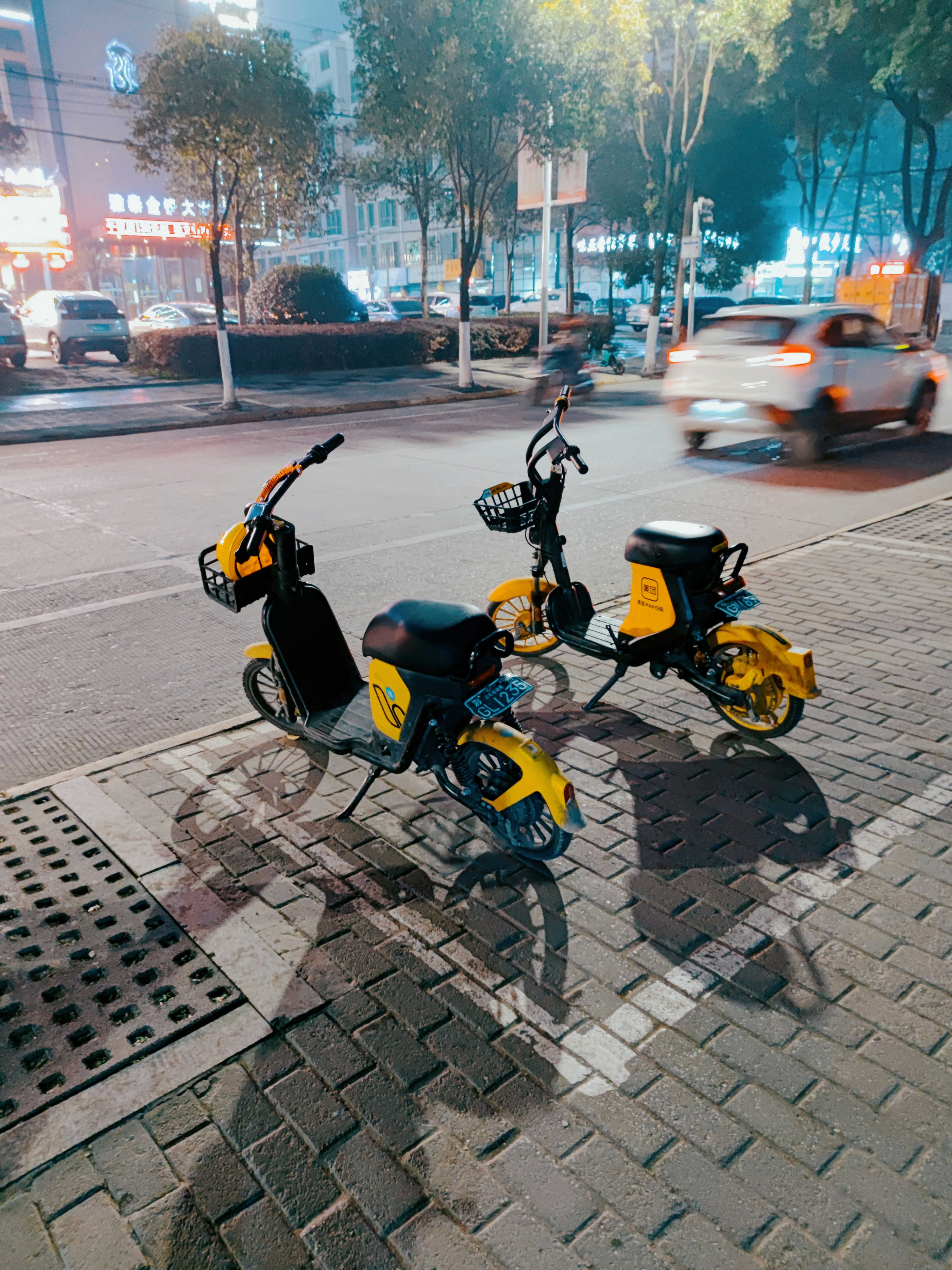 Two mopeds parked on the side of the road