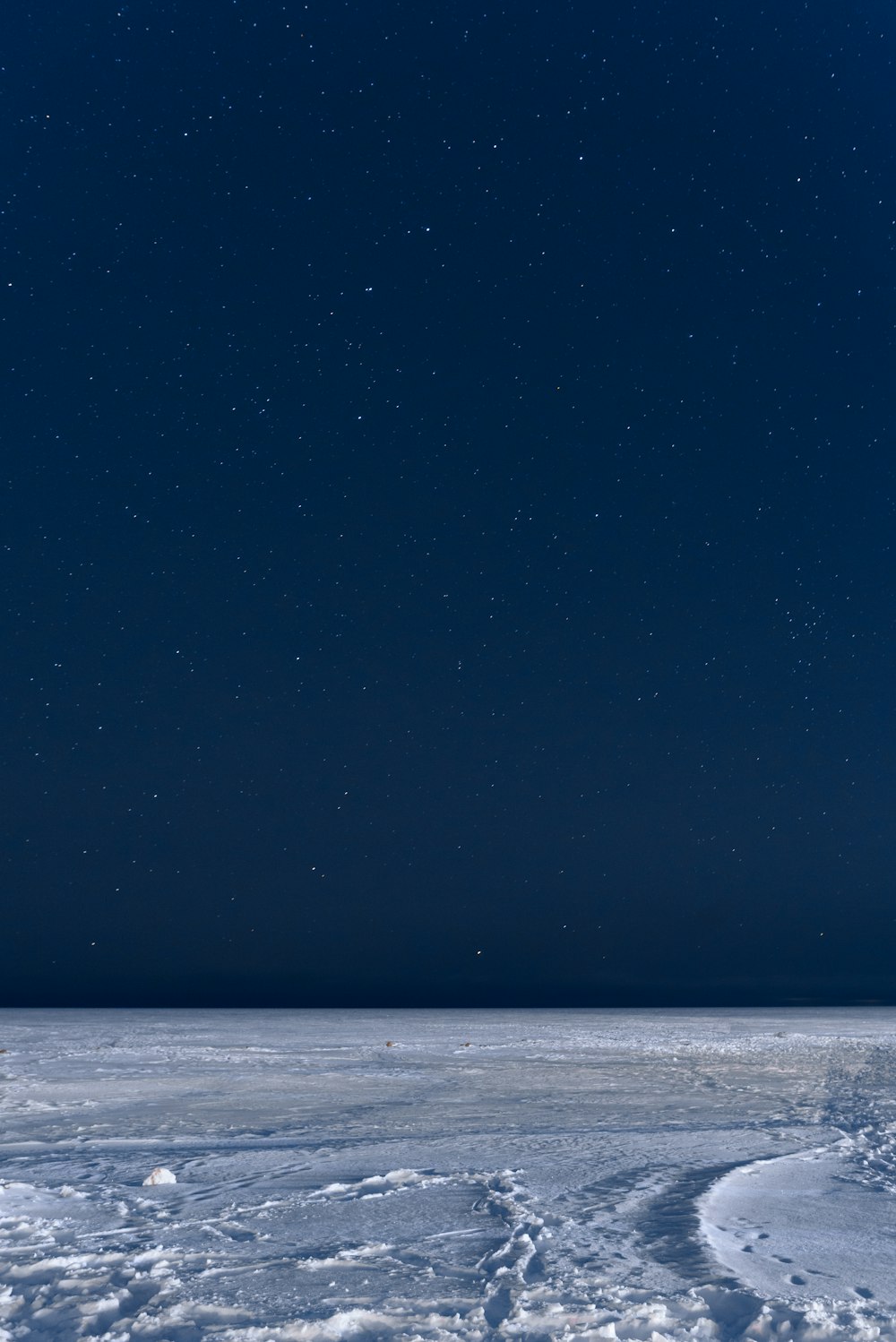 the night sky is full of stars above a vast expanse of snow
