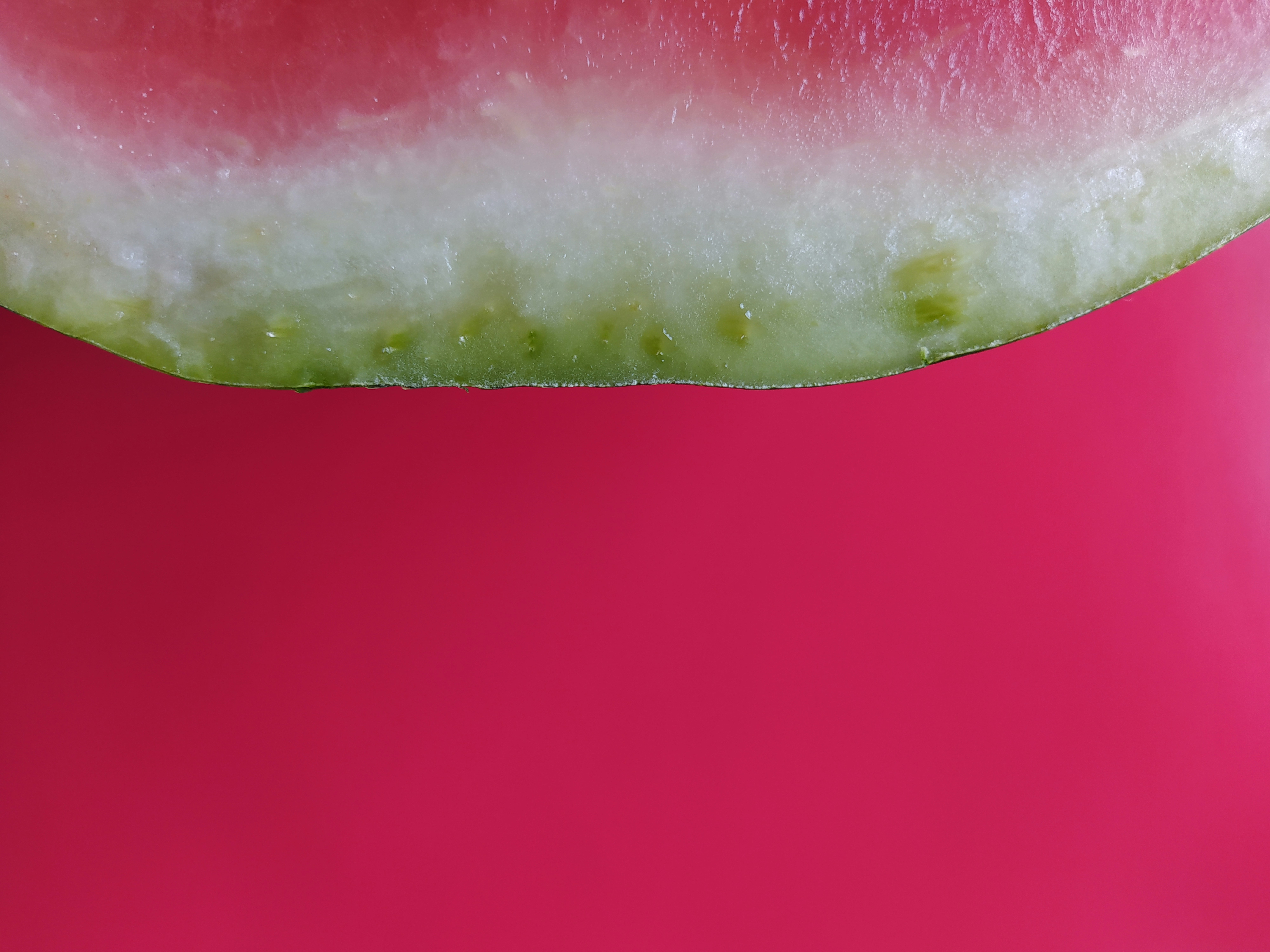 a slice of watermelon on a pink surface