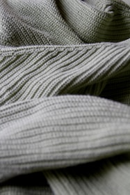A close-up view showcasing the intricate texture and patterns of green knit fabric with visible ribs and weaving details.
