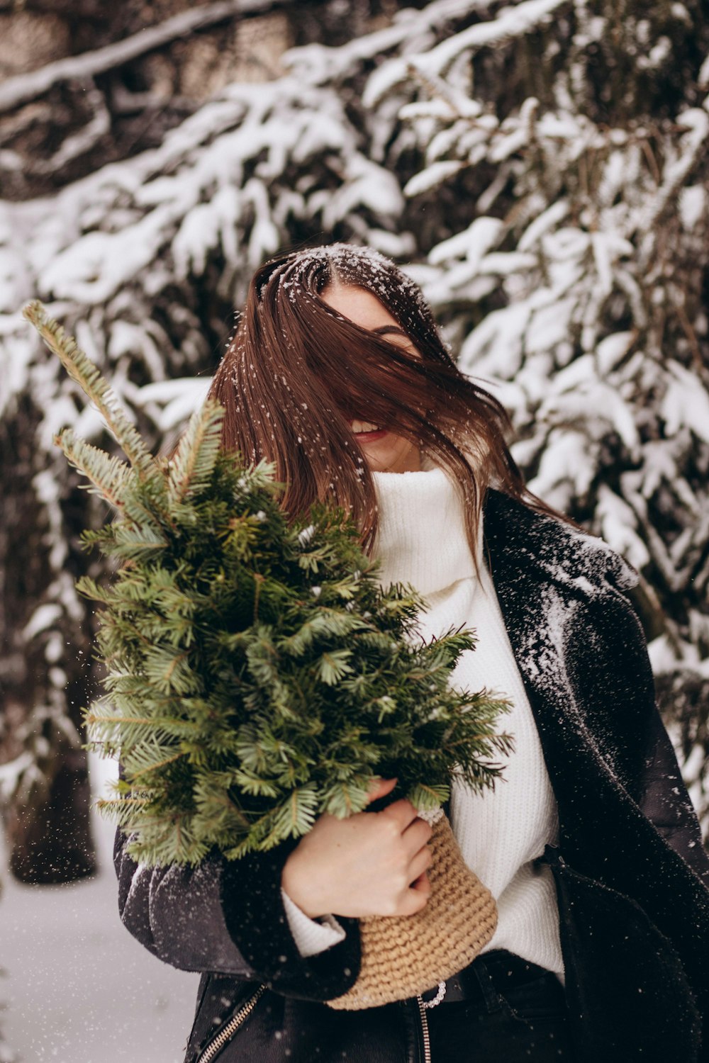 a woman holding a christmas tree in the snow