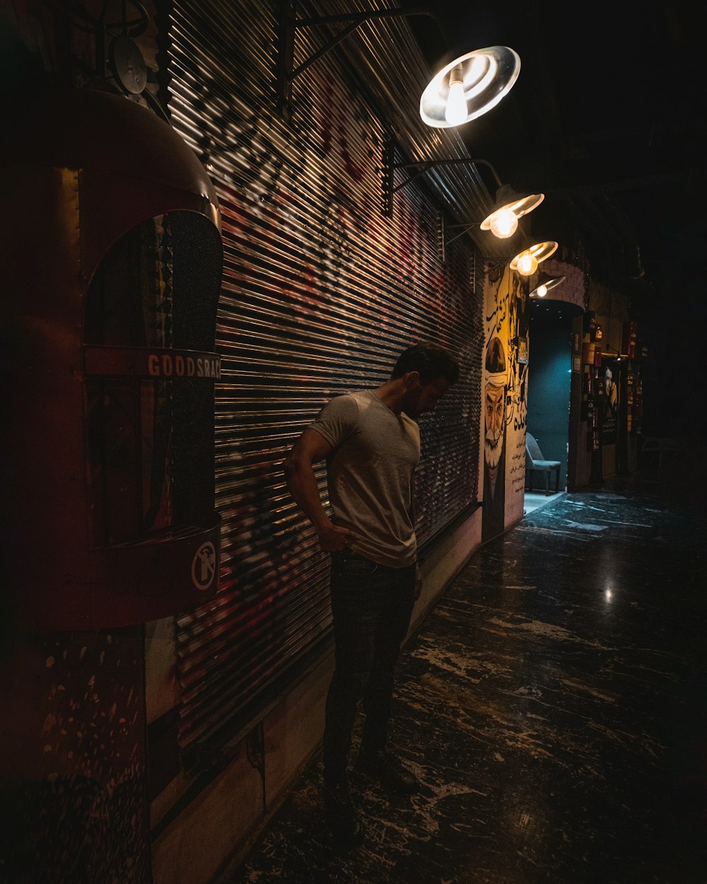 a man leaning against a wall in a dark room