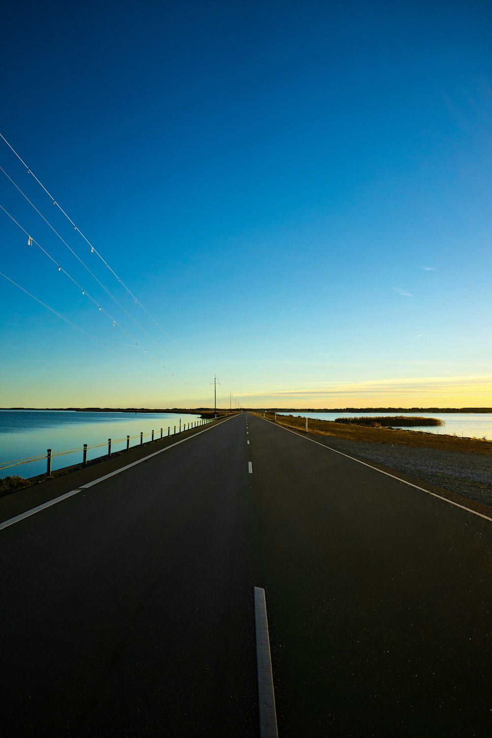 an empty road with a body of water in the background