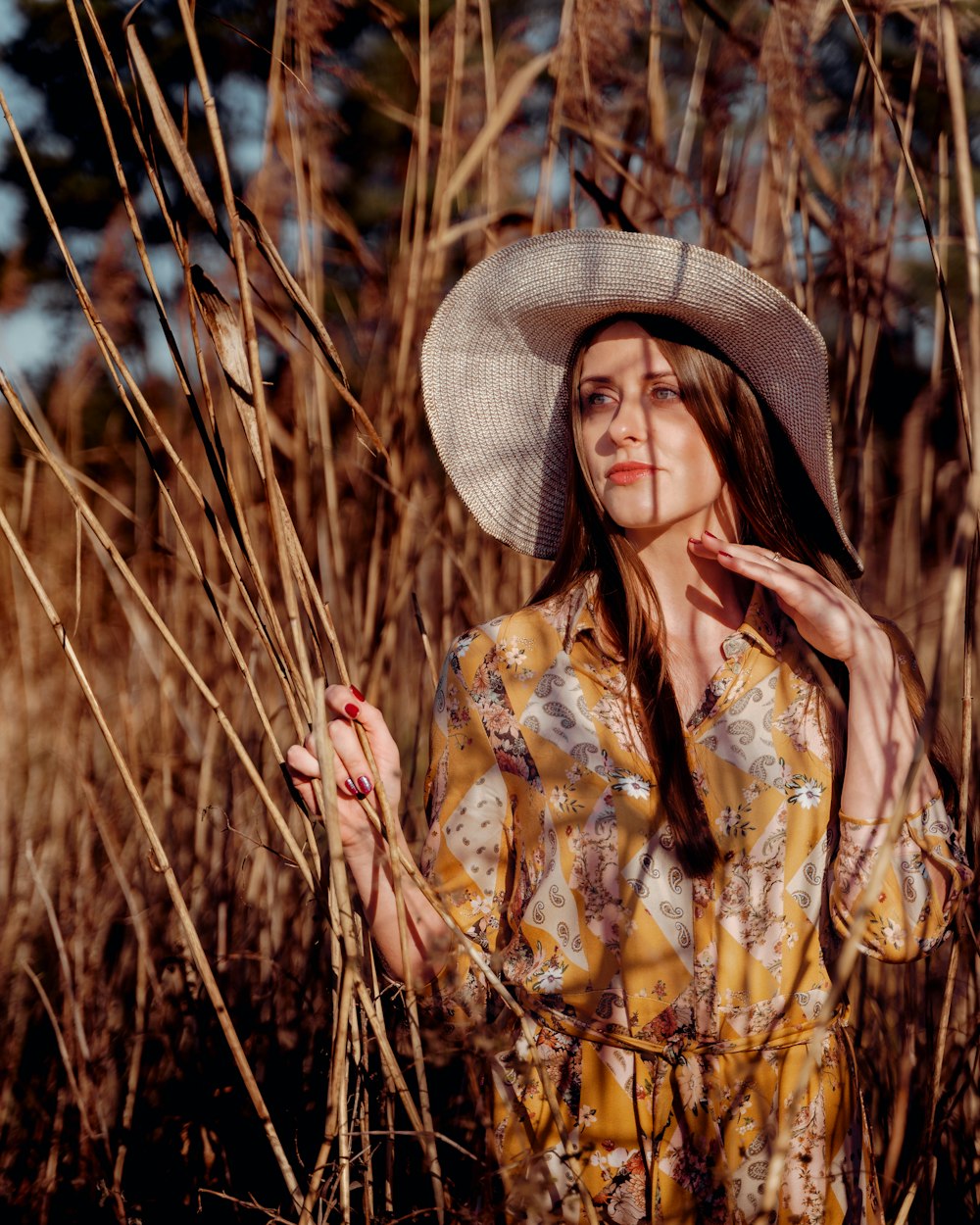 a woman wearing a hat standing in a field