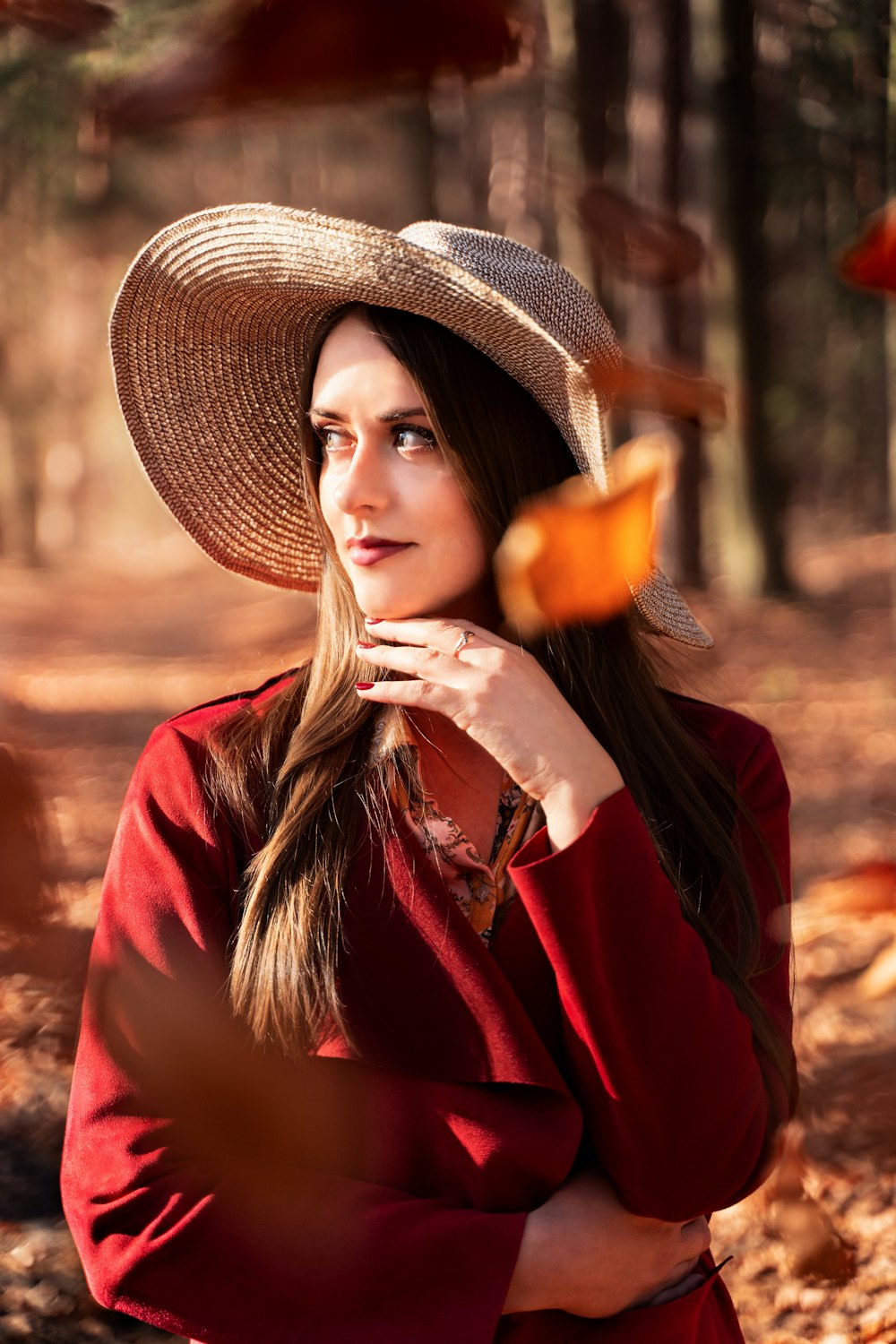 a woman wearing a hat standing in a forest