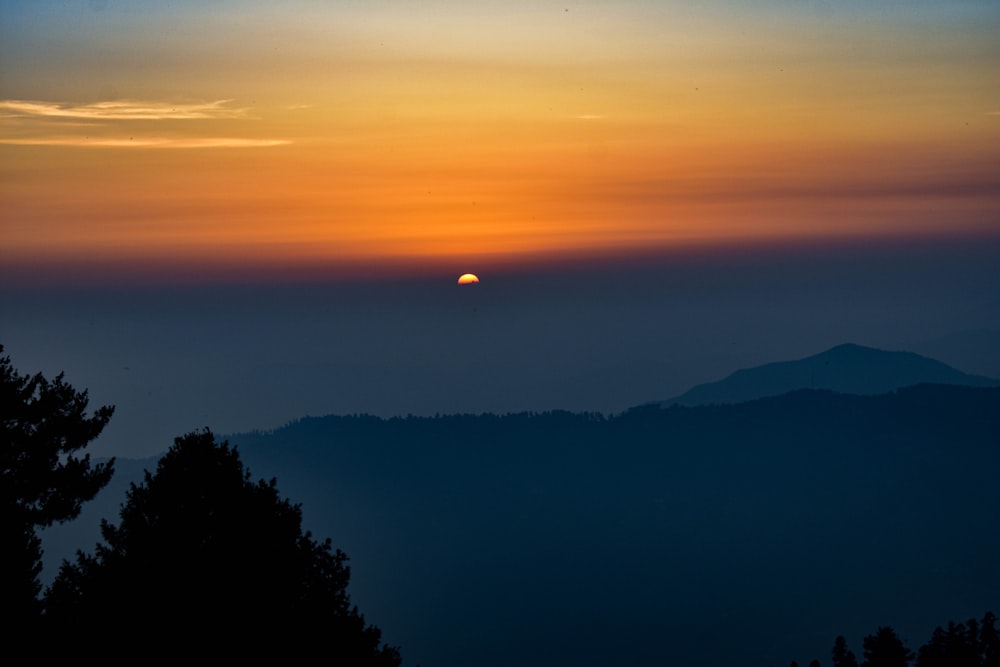 the sun is setting over a mountain range