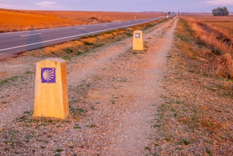 two signs on the side of a dirt road