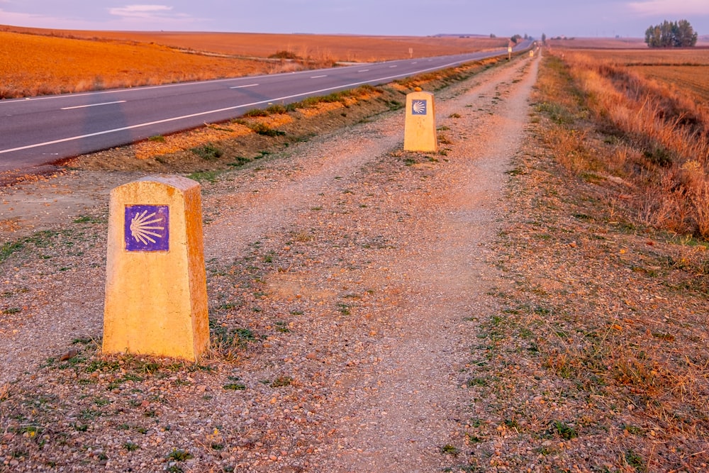 two signs on the side of a dirt road