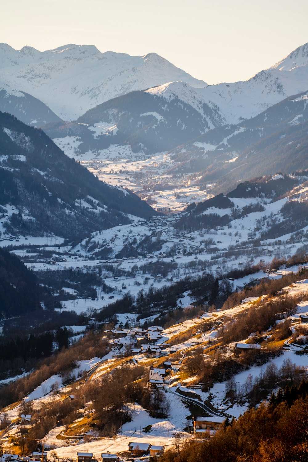 a view of a snowy mountain range with a town in the foreground