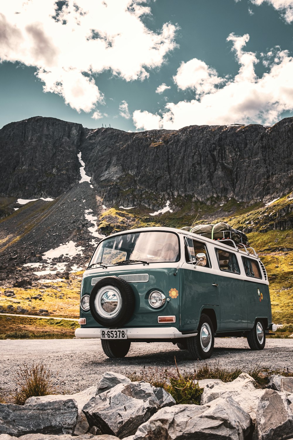 a van with a surfboard on the roof driving down a mountain road