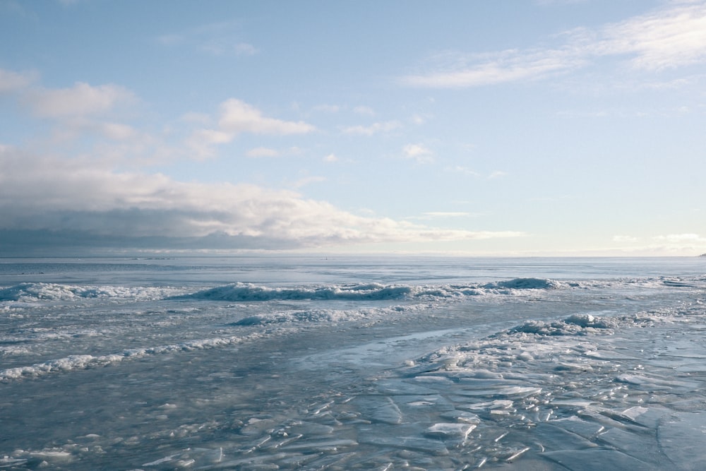 a beach covered in lots of ice under a cloudy sky