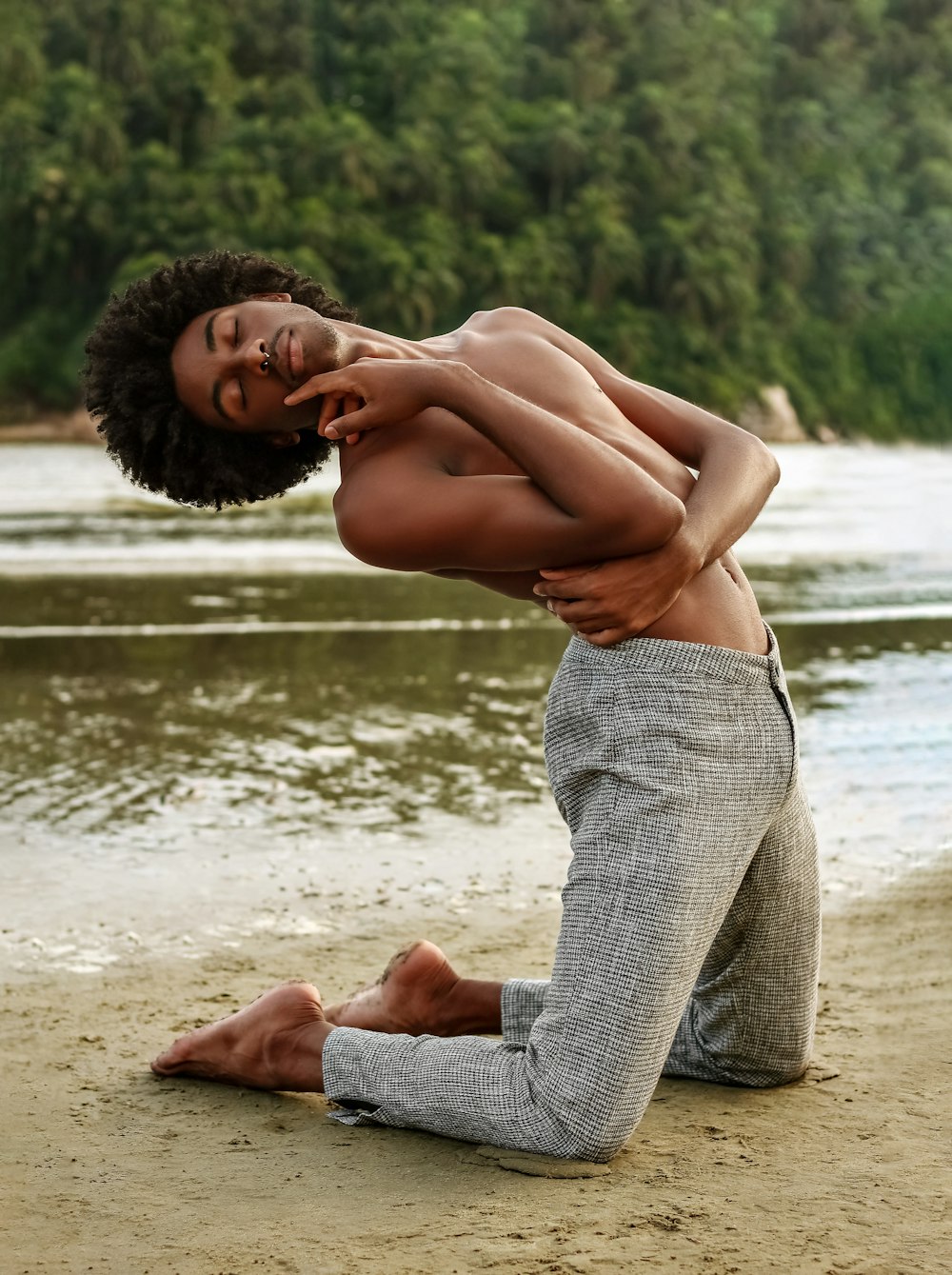 a man sitting on a beach next to a body of water