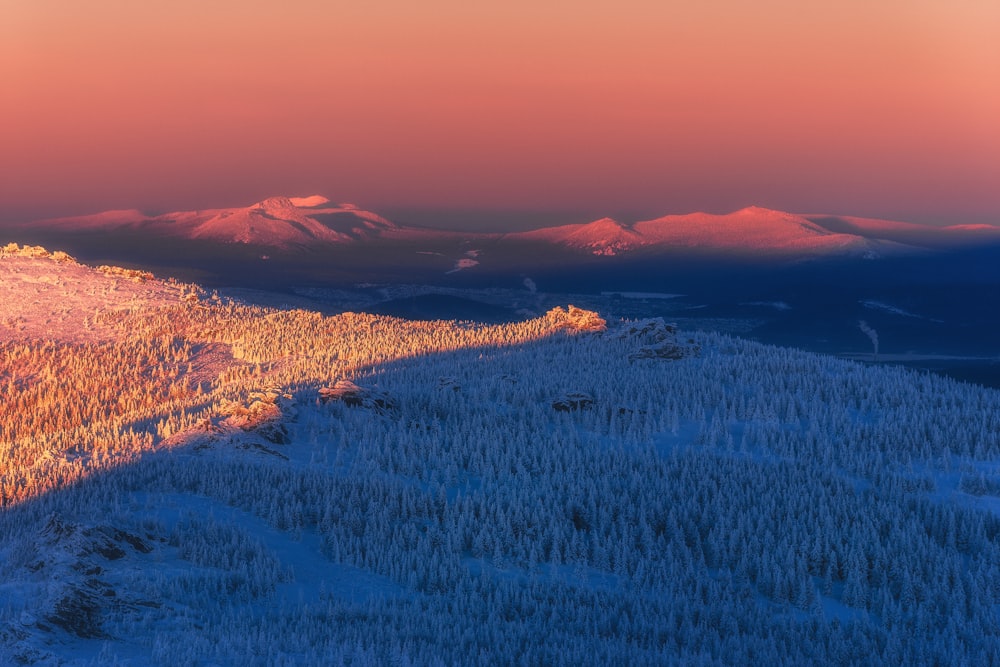 a view of a snowy mountain range at sunset