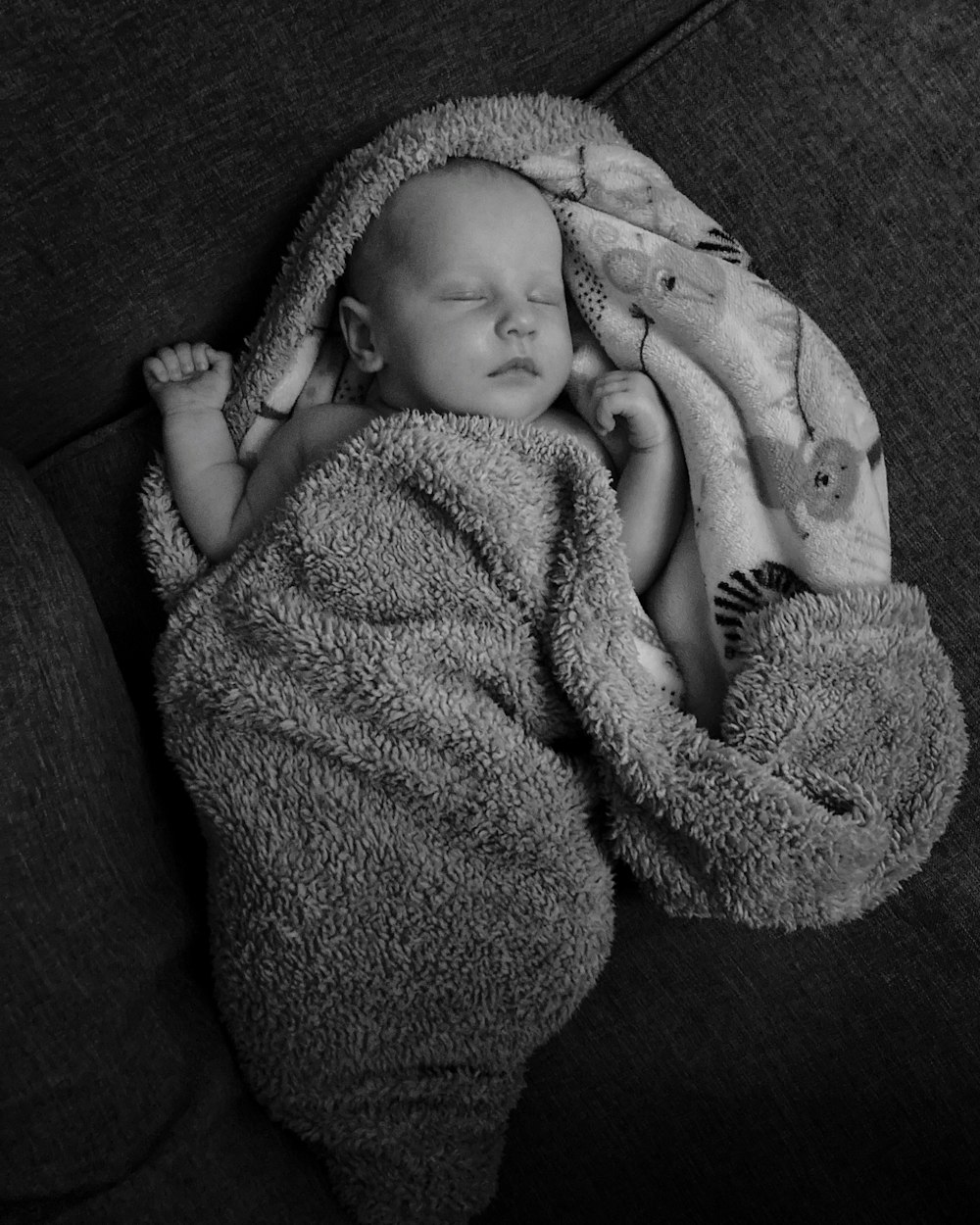 a black and white photo of a baby wrapped in a blanket