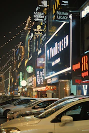 Brightly lit storefront sign glowing at night in a busy urban street.