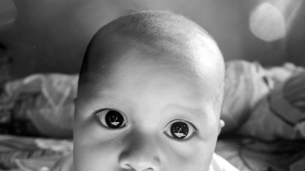a black and white photo of a baby with big eyes