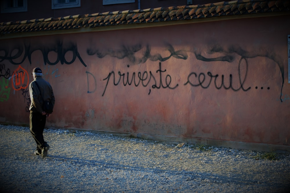 a man standing in front of a wall with graffiti on it