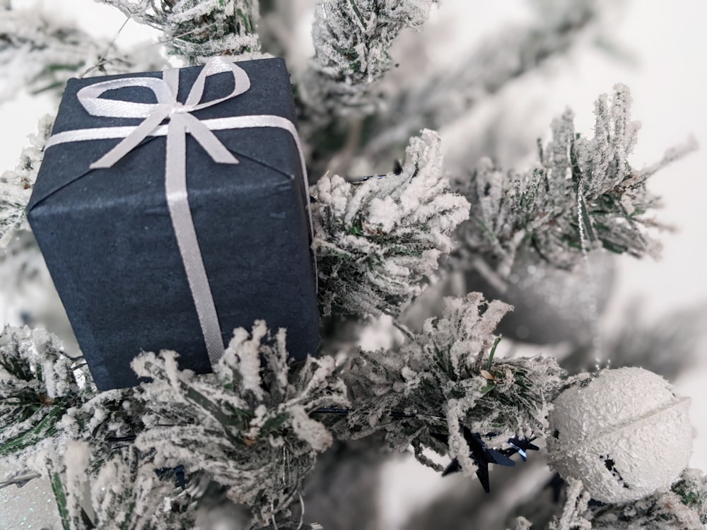 a present wrapped in a black paper sitting on top of a christmas tree