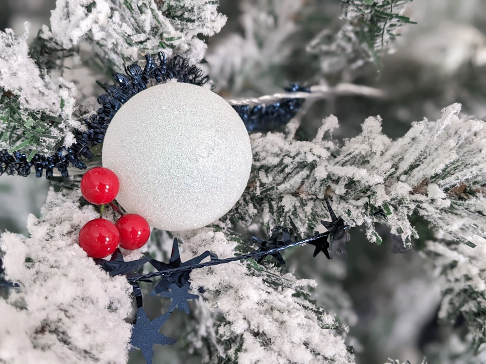 a white ornament with red berries on a tree