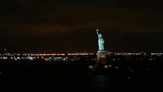 A stunning night view of New York City skyline with the Statue of Liberty in the foreground.