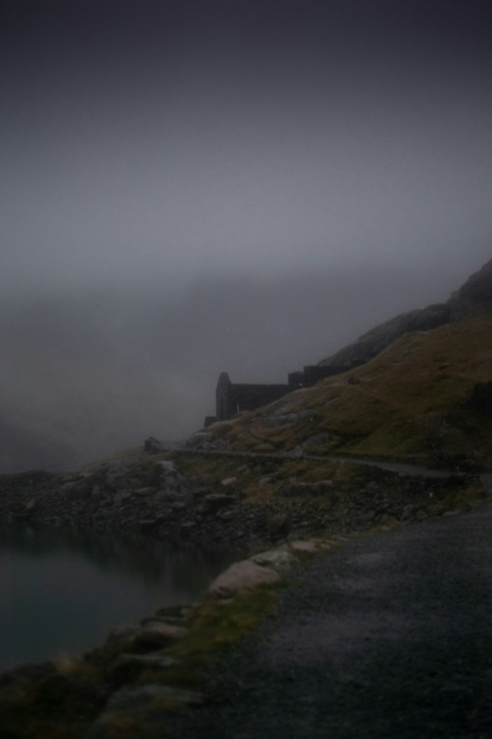 a foggy mountain with a small lake in the foreground