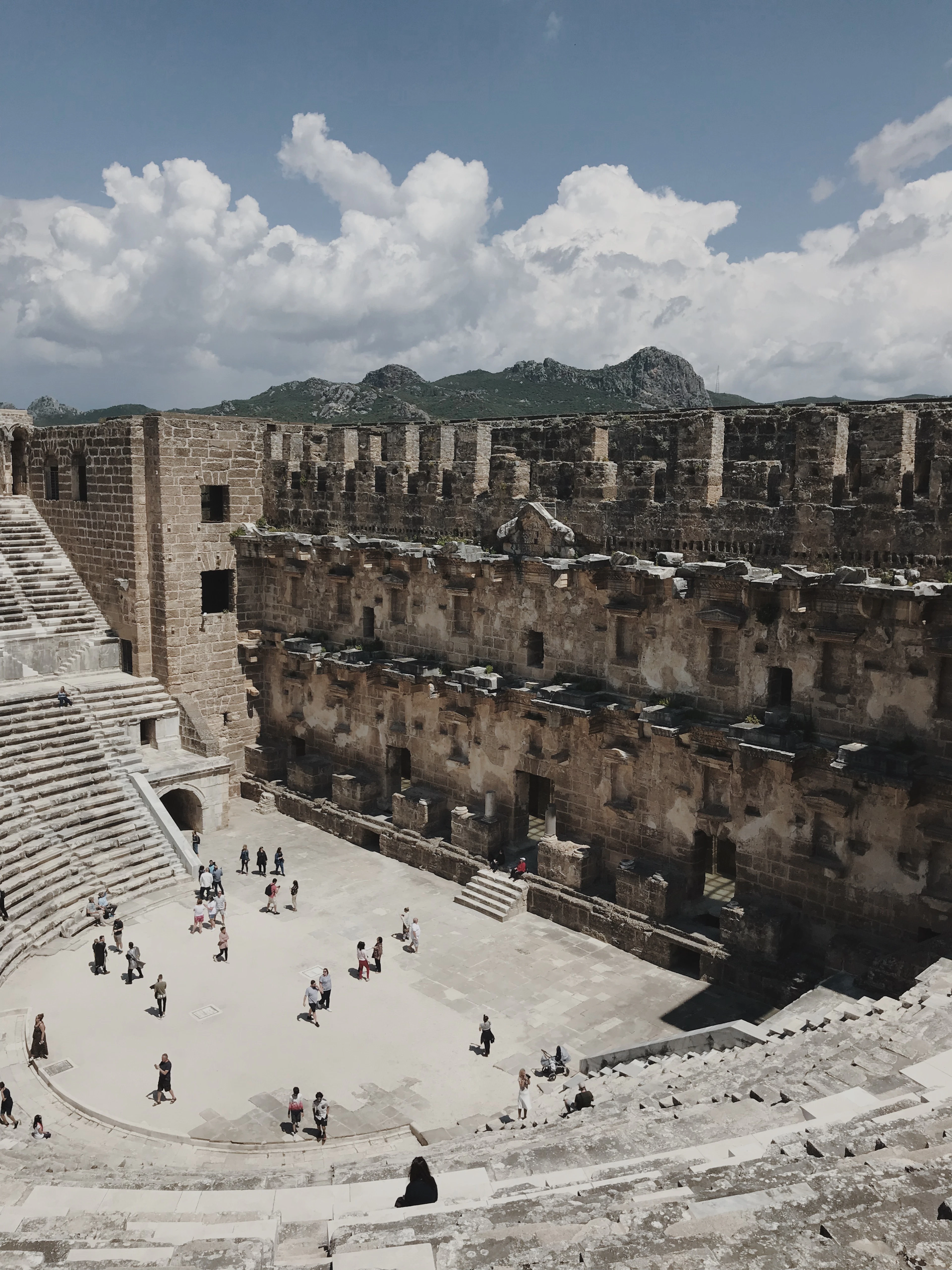 The towering, near-intact stage building of the ancient Aspendos Roman theatre under a blue sky with clouds.