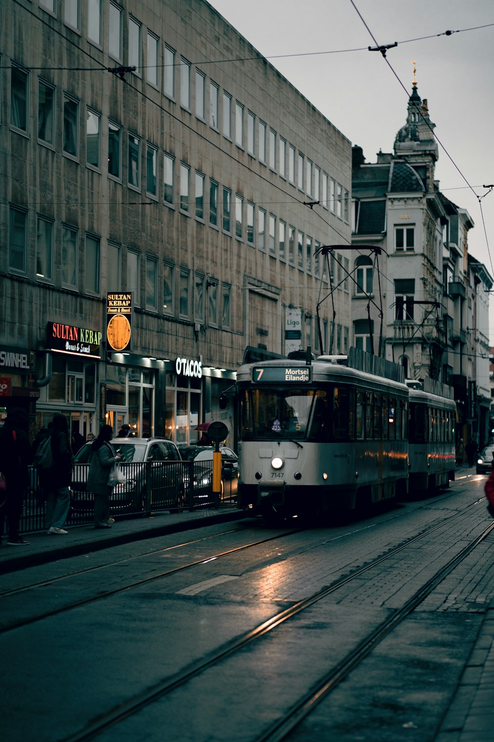 a train traveling down a street next to a tall building