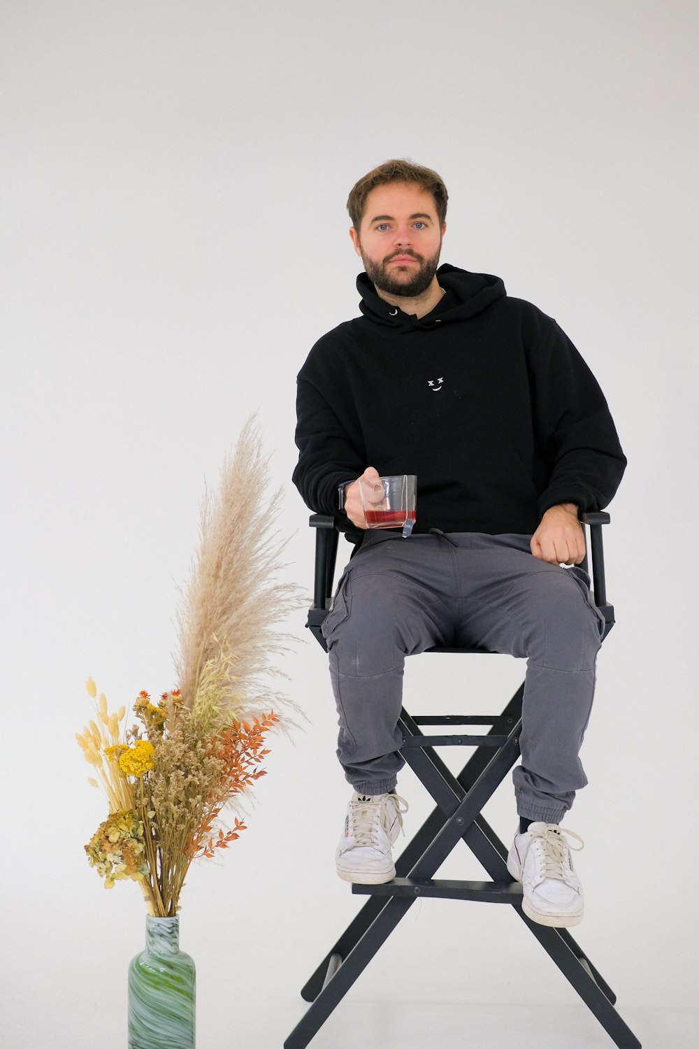 a man sitting in a chair next to a vase of flowers