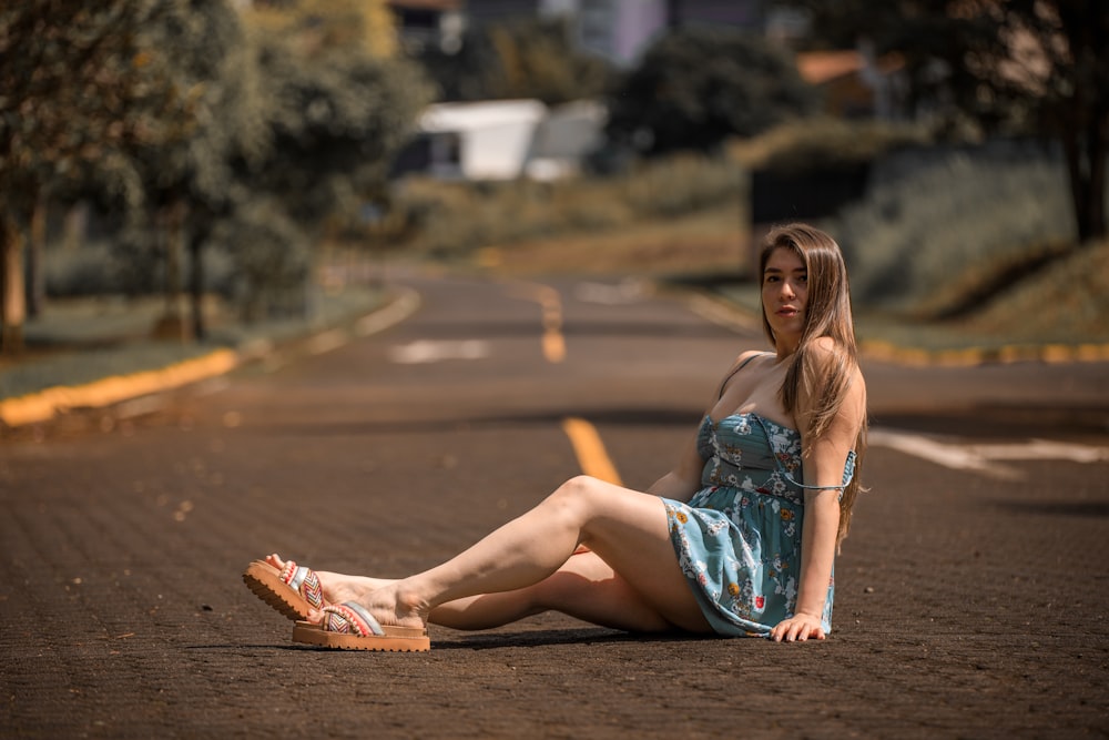 a woman sitting on the ground in a blue dress