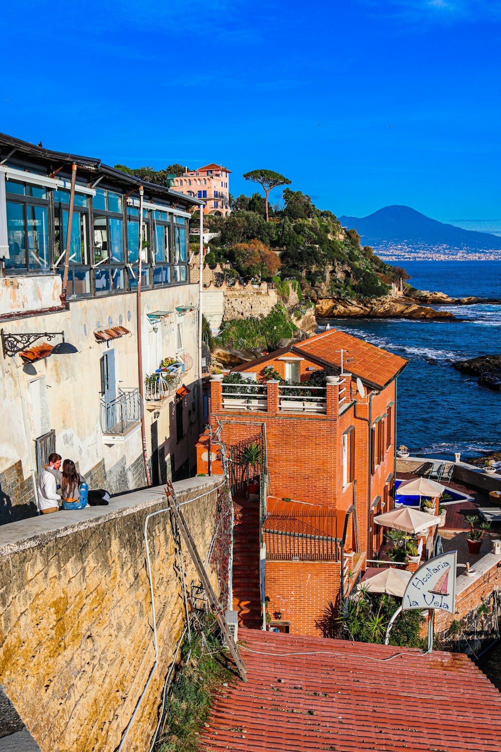 a group of people sitting on a ledge next to a body of water