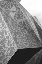 Close-up of a modern metal facade with intricate laser-cut geometric patterns in anthracite gray.