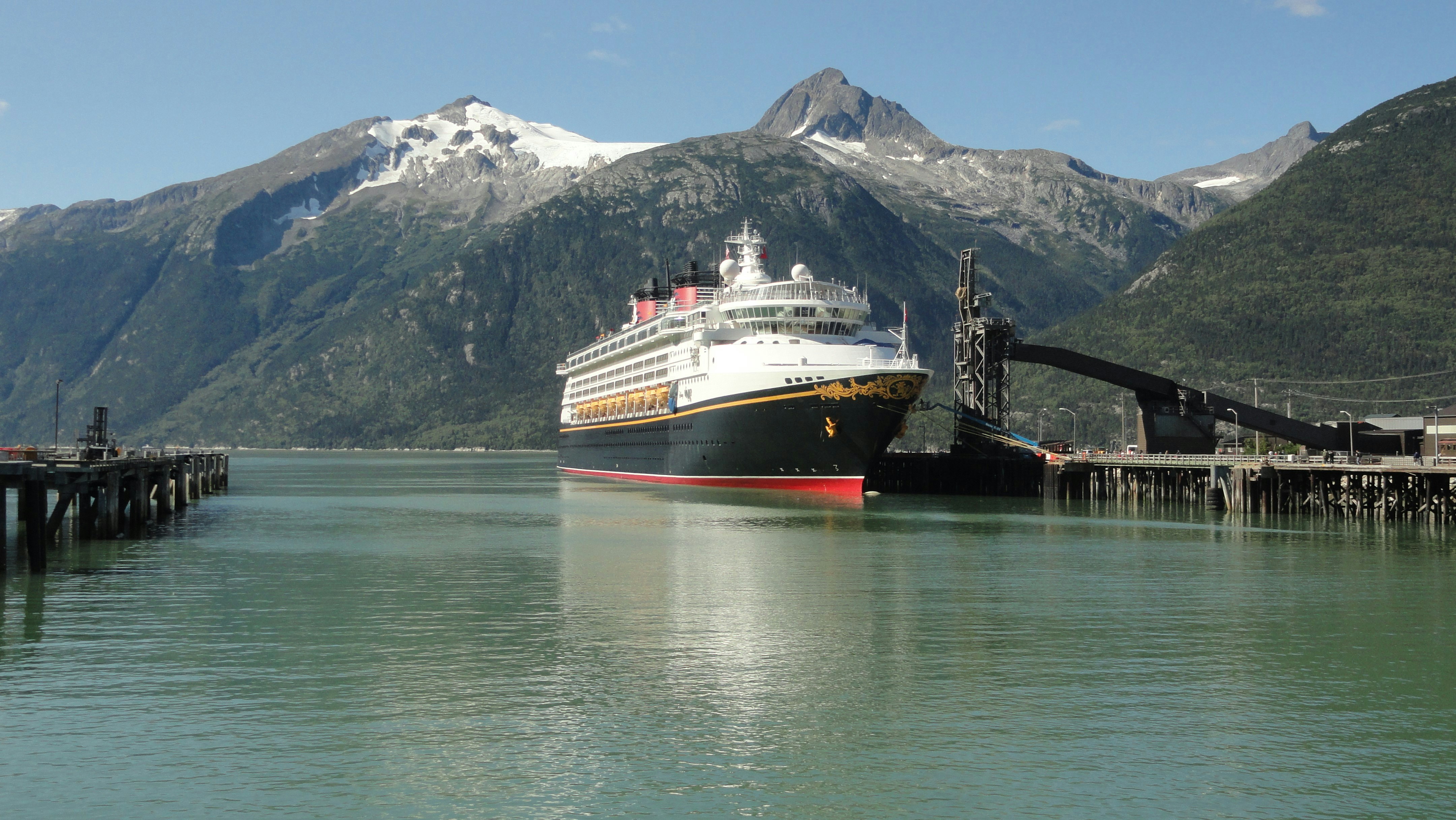 a large cruise ship docked at a pier, Disney Wonder cruise liner arriving in Skagway (Alaska)