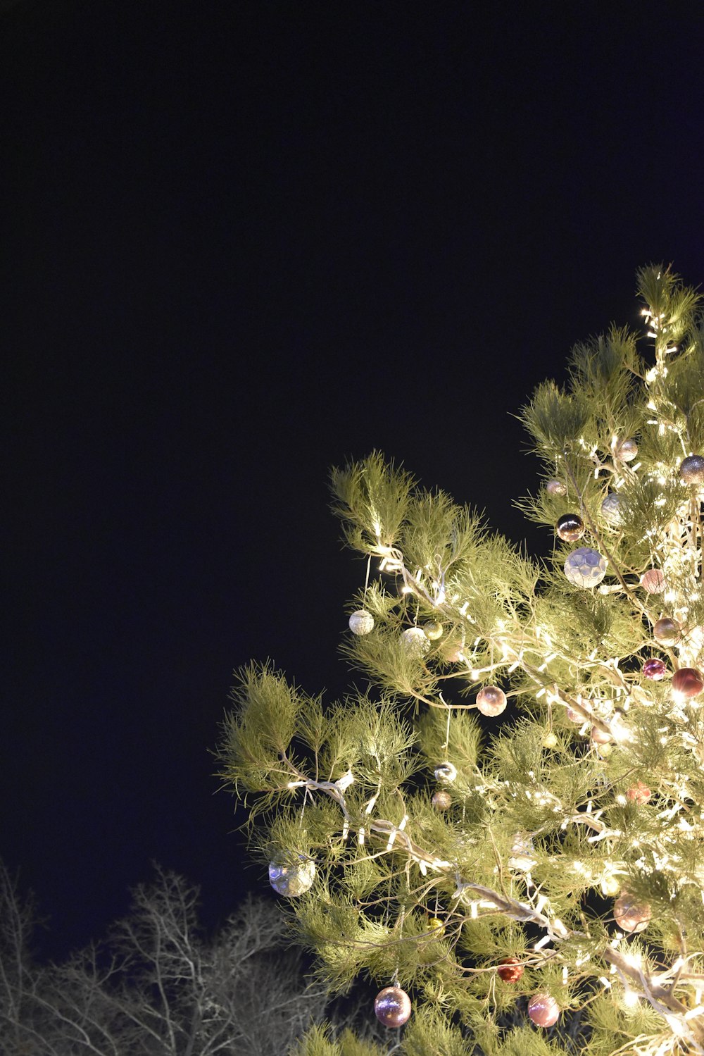 a lit up christmas tree with ornaments on it