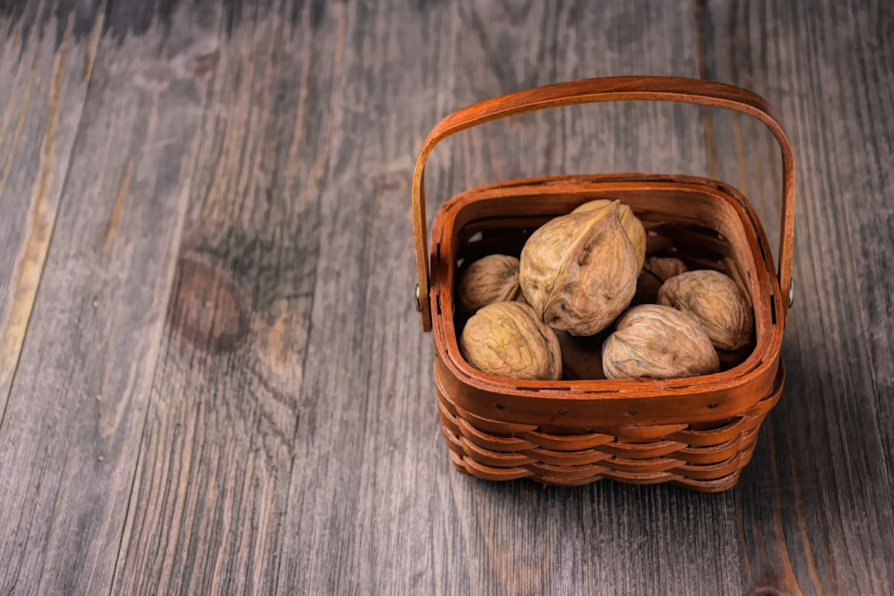 Una canasta llena de nueces sobre un piso de madera