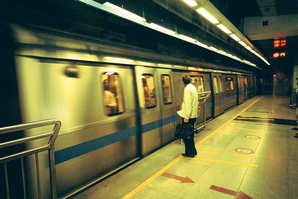 um homem está esperando por um trem em uma estação de metrô