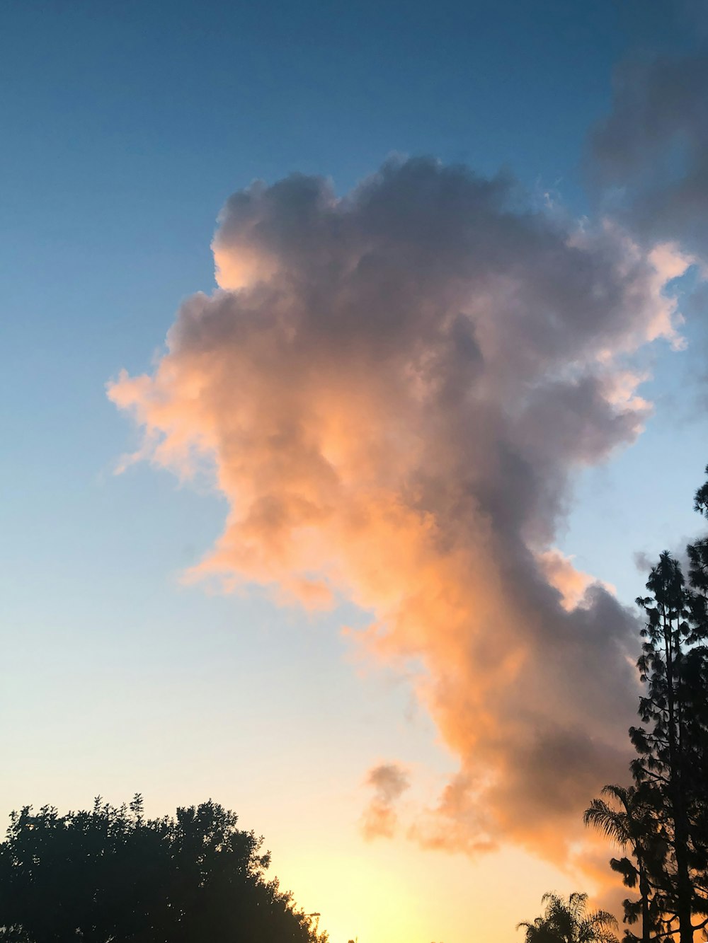 the sun is setting behind a cloud in the sky