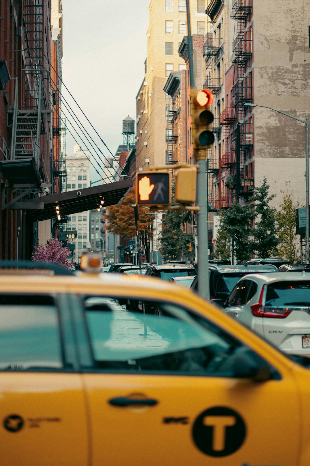 a yellow taxi cab driving down a street next to tall buildings